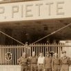 Skupina britských válečných zajatců před portálem firmy Piette